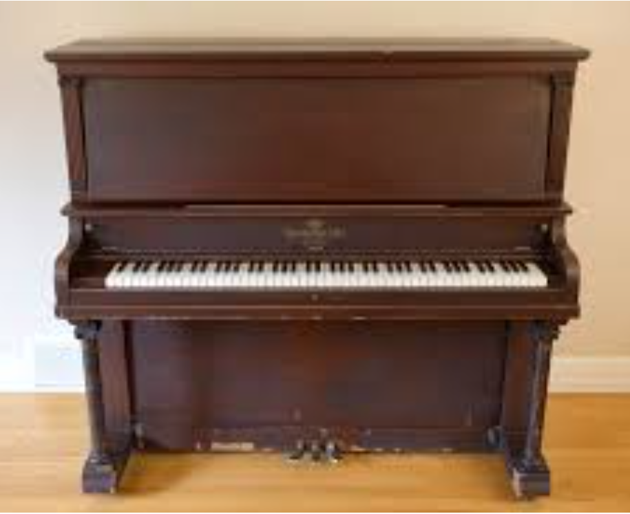 An older, upright style Heinzman piano, a little banged up.